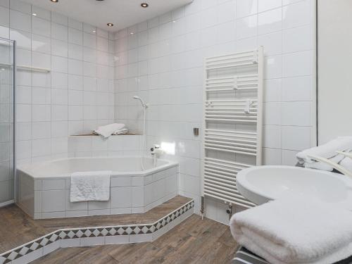 a white bathroom with a tub and a sink at Itterblick in Itter