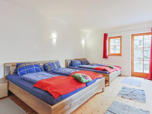 two beds in a bedroom with red and blue at Salvenblick in Hopfgarten im Brixental