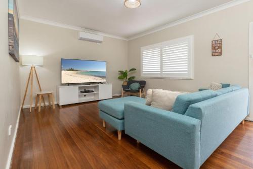 a living room with a blue couch and a tv at Cottage on Bruce in Forster