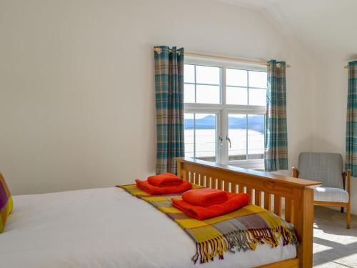 a bedroom with a bed with two orange towels on it at Wester Laggan Cottage in Skye of Curr