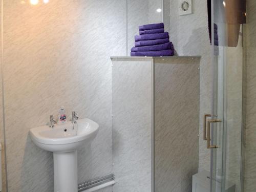 ein Badezimmer mit einem Waschbecken und einer Dusche mit lila Handtüchern in der Unterkunft Barnhill Bothy in Moffat