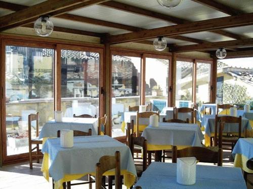 un ristorante con tavoli e sedie bianchi e finestre di Hotel Priori a Perugia