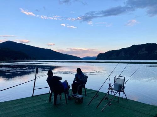 a couple of people sitting on a dock by the water at Casa David in Sviniţa