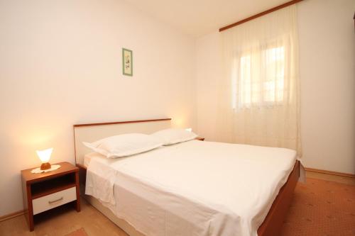 a bedroom with a white bed with a nightstand and a window at Apartments by the sea Zaklopatica, Lastovo - 8347 in Lastovo