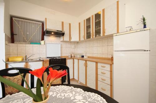 a kitchen with a table and a white refrigerator at Apartments by the sea Zaklopatica, Lastovo - 8347 in Lastovo