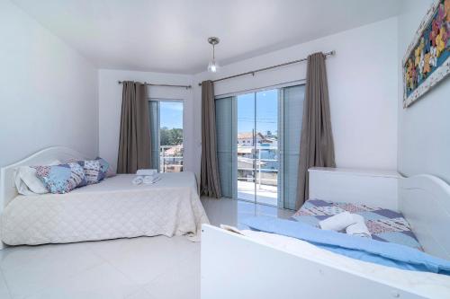 - une chambre avec 2 lits et une grande fenêtre dans l'établissement Casa de Praia em Bombinhas Beach House, à Bombinhas