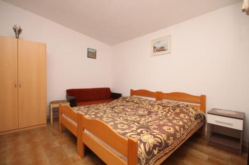 een slaapkamer met een bed en een stoel bij Secluded fisherman's cottage Lavdara, Dugi otok - 8155 in Sali