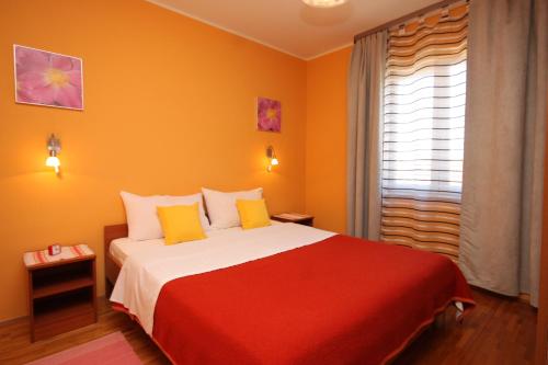 um quarto com uma cama vermelha e branca e uma janela em Apartments with a parking space Mali Losinj (Losinj) - 7964 em Mali Lošinj