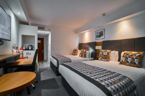 a hotel room with two beds and a desk at Holiday Inn Kenilworth - Warwick by IHG in Kenilworth