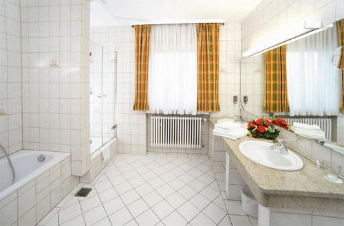 a white bathroom with a tub and a sink at Hotel Grasbrunner Hof in Grasbrunn