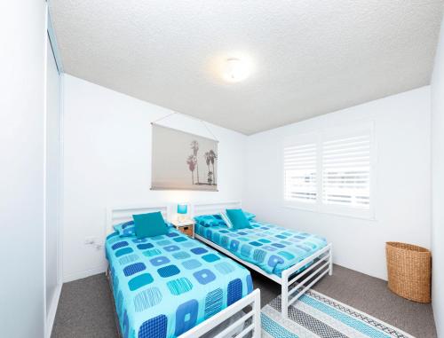 two beds in a room with white walls at Hibiscus Unit 4, 24 North St, Forster in Forster