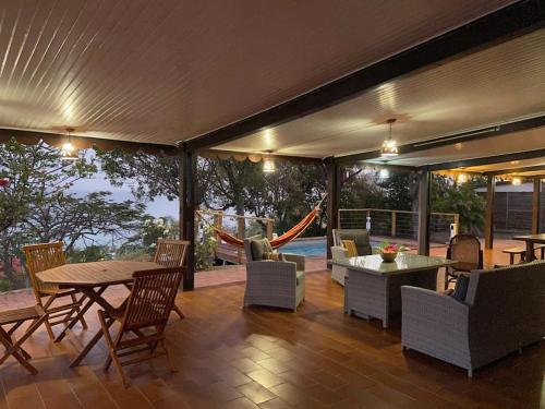 a patio with a table and chairs and a hammock at Le Caillou *** Belle villa, 4 chambres, piscine, vue mer *** in Le Diamant