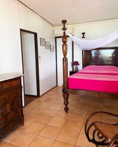 a bedroom with a bed with a pink bedspread at Le Caillou *** Belle villa, 4 chambres, piscine, vue mer *** in Le Diamant
