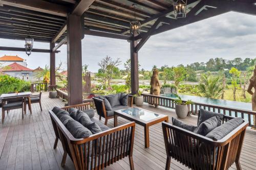 an outdoor patio with chairs and tables and a view of the water at Royal Roco Villa in Tanah Lot