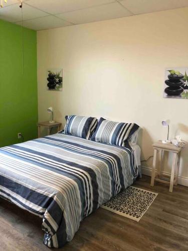 een slaapkamer met een bed met een gestreepte deken bij Aux quatre vents 4,5 grand logement privé in Lac-Mégantic