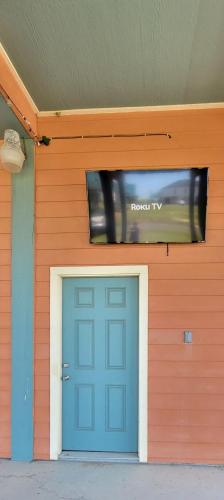 a house with a blue door and a tv above it at Fancy Nancy 2 Min Walk to Beach, Lyft, Pet-friendly in Bolivar Peninsula