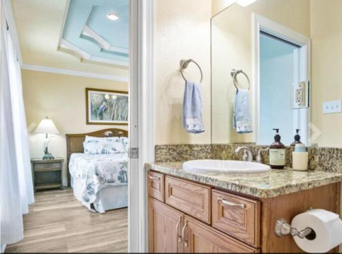 a bathroom with a sink and a bedroom with a bed at Fancy Nancy 2 Min Walk to Beach, Lyft, Pet-friendly in Bolivar Peninsula