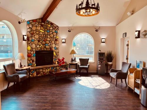 una sala de estar con una gran chimenea de piedra y sillas. en Ramada Downtown by Wyndham Anchorage, en Anchorage