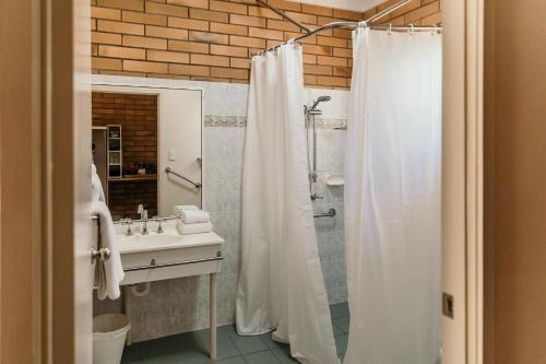 y baño con cortina de ducha y lavamanos. en Oasis Motor Inn Blackall, en Blackall