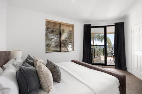 a bedroom with a large white bed with pillows at Belle De Jour, Penthouse 5, Noosa Heads in Noosa Heads