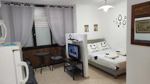 a bedroom with a bed with a television and a desk at יחידת דיור in Rishon LeẔiyyon