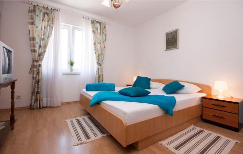 ein Schlafzimmer mit einem Bett mit blauen Kissen und einem Fenster in der Unterkunft Apartments Tresan in Tribunj