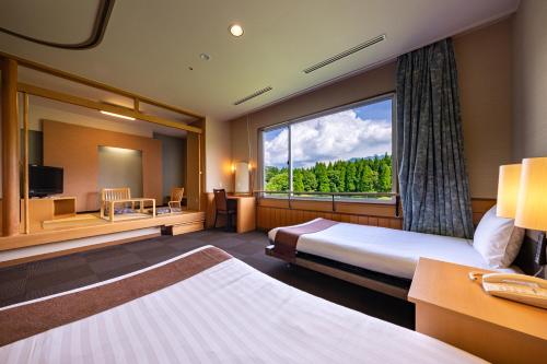 a hotel room with two beds and a large window at KAMENOI HOTEL Aso in Aso