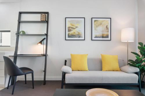 a living room with a gray couch and yellow pillows at Quattro on Astor in Brisbane