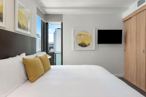 a bedroom with a large white bed with yellow pillows at Quattro Apartments in Brisbane