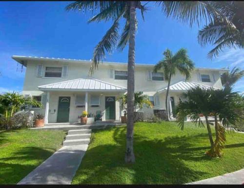 una casa blanca con palmeras delante en SeaSide Townhome, Spacious 2br 3bath Leeward Grace Bay, Providenciales, walk to beach en Providenciales