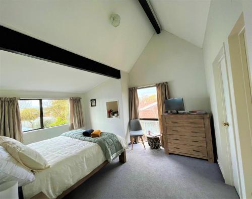 een slaapkamer met een bed en een dressoir met een televisie bij Charm on Chippendale B&B in Palmerston North