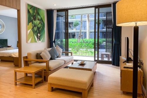 a living room with a couch and a tv at Baan Mai Khao - 2 Bedroom Luxury Condo - Direct Pool & Beach Access in Mai Khao Beach
