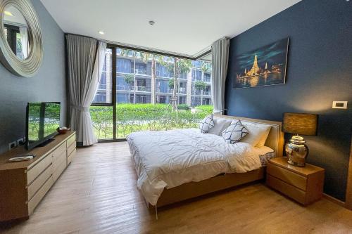 um quarto com uma cama e uma grande janela em Baan Mai Khao - 2 Bedroom Luxury Condo- Direct Pool & Beach Access em Mai Khao Beach