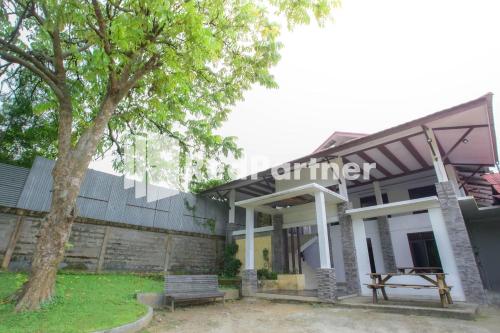 a building with a tree in front of it at Hatta Guest House Syariah near Hayam Wuruk Jelutung Mitra RedDoorz in Jambi