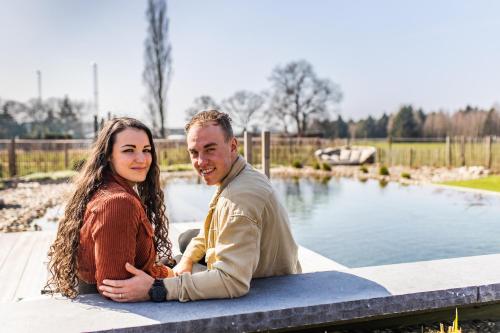 a man and a woman sitting next to a pond at guesthouse Kamiele bij Lavendine Pure in Genk