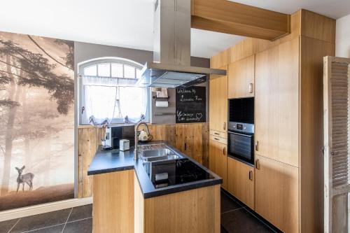 une cuisine avec des placards en bois et un comptoir noir dans l'établissement vakantiehuis Lavendine Pure, à Genk
