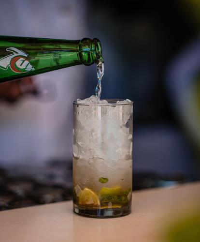 a bottle of beer is being poured into a drink at La-Paz Gardens Beacon Hotel - Vasco da Gama Goa in Vasco Da Gama