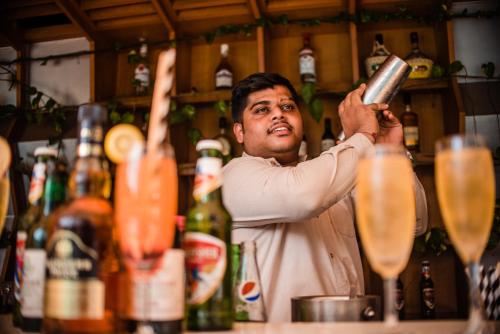 a man standing behind a bar preparing drinks at La-Paz Gardens Beacon Hotel - Vasco da Gama Goa in Vasco Da Gama