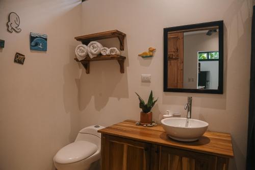 uma casa de banho com um lavatório, um WC e um espelho. em El Habita CASA SHAKO em Santa Teresa