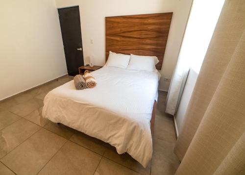 a bedroom with a large white bed with a wooden headboard at Cancun Airport Condo Hotel Apartment with pool and security in Cancún