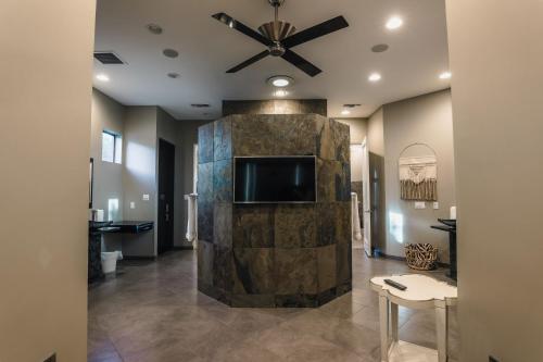 ein Wohnzimmer mit einem Deckenventilator und einem TV in der Unterkunft Exclusive, Upscale Palm Springs Estate with 5-Star Amenities in Palm Springs