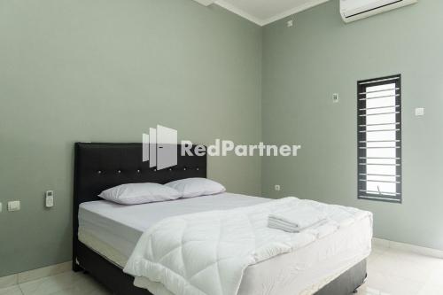 Schlafzimmer mit einem Bett mit weißer Bettwäsche und weißen Kissen in der Unterkunft Athena House Syariah Near The Park Mall Solo Baru Mitra RedDoorz in Sukoharjo