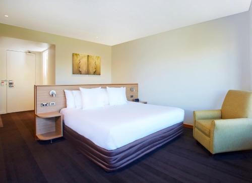 a hotel room with a bed and a chair at Crowne Plaza Canberra by IHG in Canberra