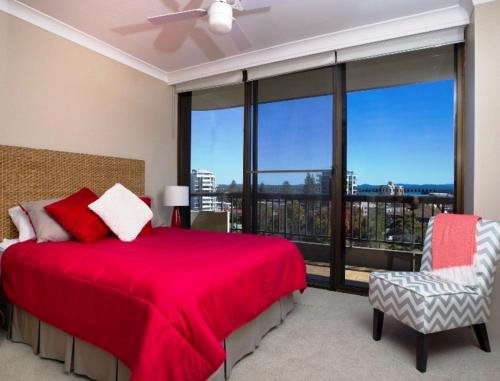 a bedroom with a red bed and a large window at Pinnacle 701 in Forster