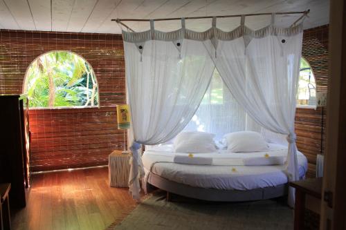 Schlafzimmer mit Himmelbett und weißen Vorhängen in der Unterkunft Villa spa Grand Anse in Petite Île
