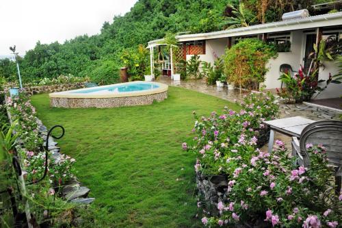 a yard with a swimming pool and some flowers at Bellevue Raiatea in Uturoa
