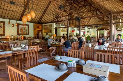 a group of people sitting at tables in a restaurant at Desamuda Village in Seminyak