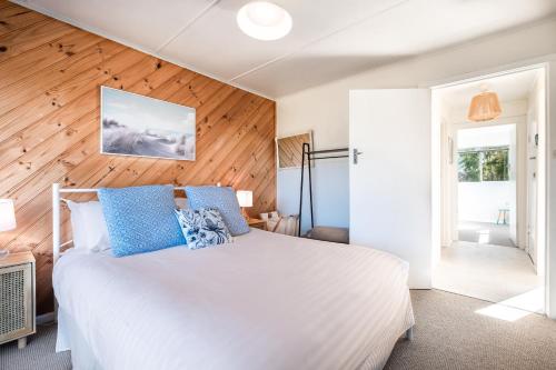 a bedroom with a white bed and a wooden wall at Le Shack - Freycinet Holiday Houses in Coles Bay