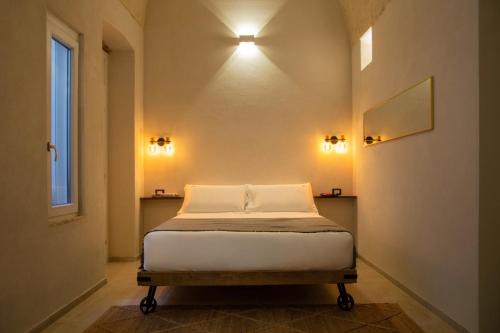 a bed in a room with two lights on the wall at ELLEMENTS - Luxury Rooms in Brindisi