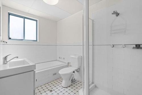 a white bathroom with a toilet and a shower at Ocean Palms Unit 2 in The Entrance